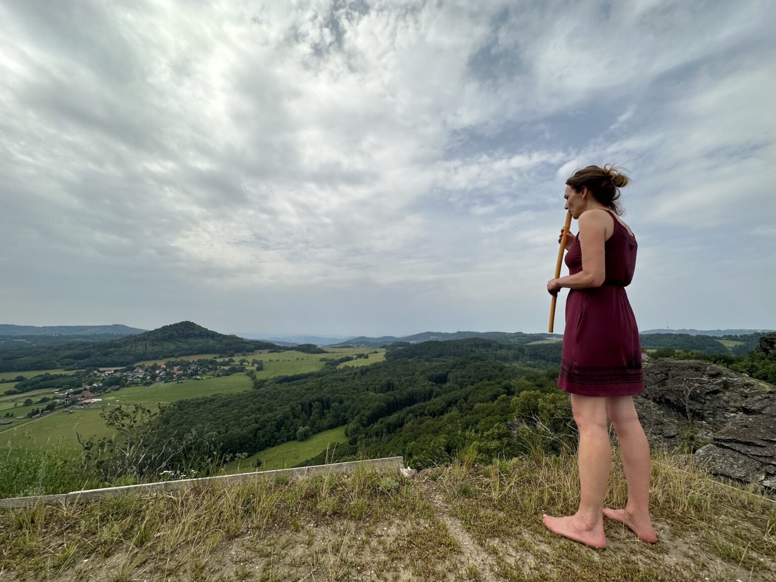 Žena stojí na skále a dívá se do krajiny v období životní změny