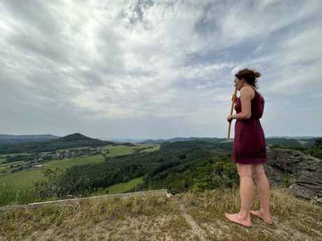Žena stojí na skále a dívá se do krajiny v období životní změny